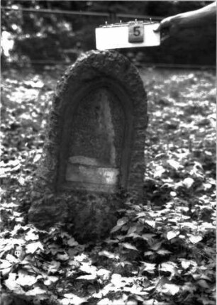 Grabstein 5 (Index: 100105637) Material: Muschelkalk, weiße Marmorplatte Zustand: Platte bis auf den untersten Teil weggebrochen, vom Text nur Schlußformel erhalten Maße HxBxT: 116x54x30 cm Beschreibung: konische, rusticaartige Stele, Spitzbogenabschluß, Schriftplatte: Grabstein 5