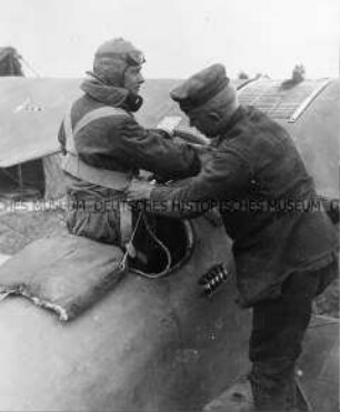 Einem Piloten wird der Fallschirmgürtel angelegt