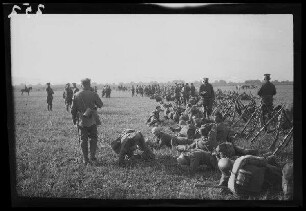 Bei Focșani (Rumänien): Soldaten neben aufgestellten Gewehren in lockerer Haltung auf einem weiten Feld (Nahaufnahme) ("Kaiserparade")