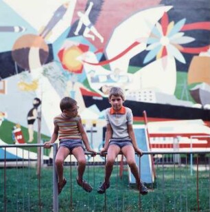 Zwei Jungen auf dem Geländer eines Spielplatzes sitzend