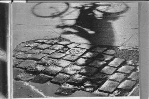 Formalismus. Straßenplaster mit Schatten eines Radfahrers