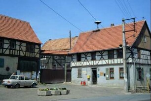 Platz mit Gebäude der Gemeindeverwaltung; Hofzufahrt mit überdachtem Hoftor