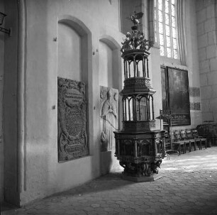 Bernau, Kirchgasse 8. Stadtpfarrkirche St. Marien (um 1240; 1400/1519 Umbau; 1979/1989 Renovierung). Chorumgang. Ansicht mit hölzernen Taufe mit Aufsatz (1606), zwei Nischen mit Grabsteinen, Pastorenbildnis und Altarweihinschrift (1479). Ansicht von Westen