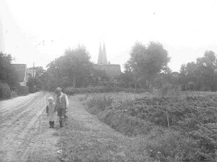 Zwei Kinder auf einem Feldweg, im Hintergrund eine zweitürmige Kirche, vielleicht Altenbruch?