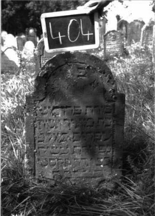 Grabstein 404 (Index: 100102815) Material: Sandstein Zustand: stark verwittert, Abplatzungen Maße HxBxT: 80x49x7 cm Beschreibung: Stele, eingezogener Rundbogenabschluss, Schriftfeld eingetieft: Grabstein 404