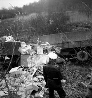 A1: Verkehrsunfall: Lastzug stürzt Böschung hinab: Unfall-Lastzug in Teilansicht, Ladung Herde, Kartons, Rohre, Füllmaterial herausgefallen: vorne Polizist bei Betrachten des Schadens: hinten Wiesen, Sträucher