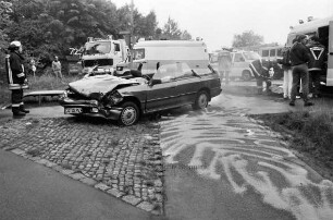 Ostring: Verkehrsunfall mit zwei Pkws: verunglückter Pkw mit eingedrückter Front und abgetrenntem Dach: hinten Rettungs-, Feuerwehr- und Polizeifahrzeuge: dazwischen Rettungskräfte: vorn abgestreute Straße: 11. Juni 1999