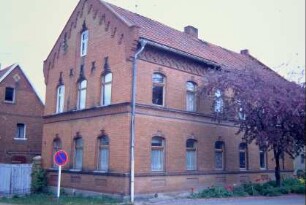 Bauernhaus am Dorfplatz, großer roter Backsteinbau mit vielen Verzierungen am Ortgang und Fries am Gesims