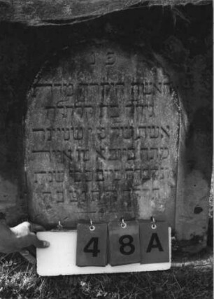 Grabstein 48 (Index: 100113841) Material: Sandstein Zustand: oberer Teil abgebrochen Maße HxBxT: 75x58x15 cm Beschreibung: Stele mit Spitzgiebel und Bogenfries, vertiefter Textteil in Form einer Stele mit Rundbogen: Grabstein 48A