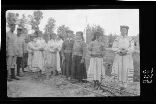 Einheimische Frauen in Tracht bzw. festlicher Kleidung auf dem Gleis einer Kleinbahn stehend