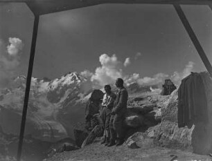 Auf dem Gipfel : Zwei Bergsteiger stehen auf dem Gipfel des Languard. Im Hintergrund zwischen den Wolken ist der Bernina erkennbar.