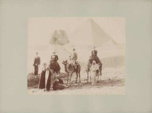 Besucher auf Kamelen vor Sphinx und Pyramiden von Gizeh in Ägypten
