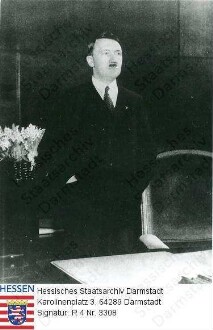 Hitler, Adolf (1889-1945) / Porträt als Reichskanzler in seinem Arbeitszimmer in der Reichskanzlei, an Schreibtisch stehend, Kniestück