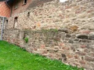 Kirchhofmauer im Südsüdosten mit Werksteinen im Mauersteinverband sowie Brüstungsversatz (des ehemaligem Wehrgangs) über Kirchhof