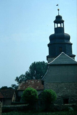Kirche, Ansicht von Westen; der aus dem 13. Jh. stammende Bau wurde 1742 grundlegend verändert; links Pfarrhaus