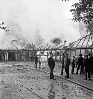 Schleushörn: Brand: Trabergestüt und Reitstall "Schleushörn" von Klaus Martens: brennender Stall mit Reetdach: vorn rechts Zuschauer: in der Mitte Feuerwehrmänner beim Löschen