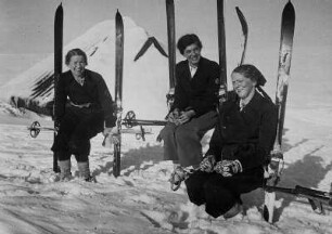 Rast während eines Skiausfluges im böhmischen Teil des Riesengebirge an der Elbquelle. Drei Frauen sitzen auf ihren Ski
