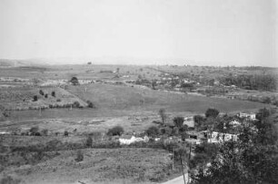 Blick in ein Tal : Blick in ein Tal mit Grasland bei Amparó. Am Fuße des Hügels verläuft eine Straße, an der Häuser stehen. Vereinzelt stehen Bäume oder Baumgruppen in der Landschaft.