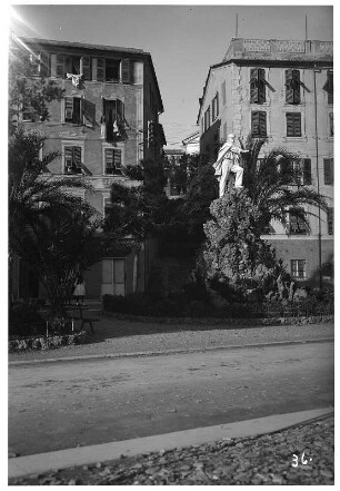 Genua. Straße mit Denkmal vor einer Häuserzeile