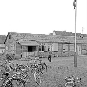 Sporteinrichtungen: Sportanlage am Kortenkamp: Baracke als Sportlerheim: Sportverein (SV) Großhansdorf von 1942 e. V.: links davor Fahrräder: in der Mitte Mann: rechts Fahnenmast: im Hintergrund Wohnblocks