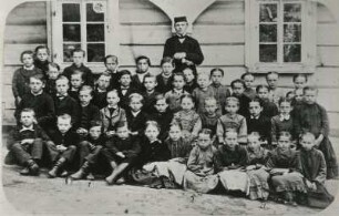 Sächsische Schweiz, Hinterhermsdorf. Schulklasse mit dem Kirchschullehrer Johann Gotthelf Claus vor dem Schulgebäude. Fotografie auf Pappe; 16,5 x 23,2 cm. Sebnitz: Heimatmuseum