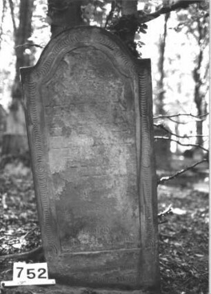 Grabstein 752 (Index: 99900391) Material: Sandstein Zustand: stark verwittert Maße HxBxT: 120x54x10 cm Beschreibung: Stele mit Konvexbogenabschluss, umlaufender Scheibenfries Symbolik: Scheibenfries: Grabstein 752