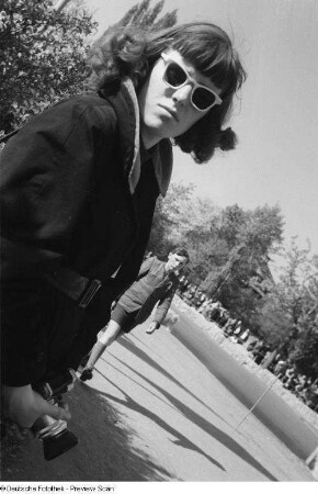 Portrait Renate Rössings mit Sonnenbrille und Fotoapparat am Rand der Piste beim 6. Leipziger Stadtparkrennen