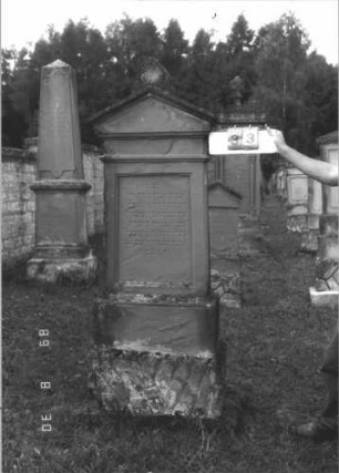 Grabstein 33 (Index: 99609669) Material: Sandstein Zustand: stark verwittert, versalzen Maße HxBxT: 189x65x30 cm Beschreibung: Stele, Giebelabschluß mit Verdachung, Mittelpalmette, Schriftfeld rechteckig eingetieft, getreppter Sockel, unten Rusticaimitat: Grabstein 33