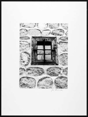 Spanien. Kleines Holzfensterchen mit schmiedeeisernem Fensterkreuz an einem Mauerwerk (Hauswand?)