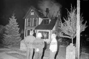 Brand: Zweifamilienhaus: vorn und im Haus Feuerwehrmänner und zwei Männer: hinten Mitte Brandruine: Nacht