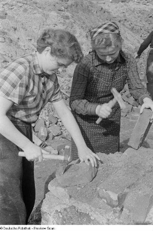 Junge Frauen bearbeiten Ziegelsteine auf der Baustelle Chausseehaus