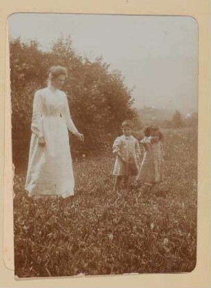 Eine Frau im hellen Kleid und zwei Kinder auf einer Wiese in Aussee