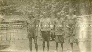 Gruppenbild vierer afrikanischer Männer vor einem Zaun