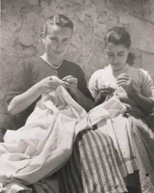 Sorso. Sardinien. Zwei Frauen sitzen vor einem Haus und sticken