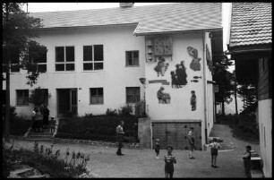 Imst: SOS Kinderdorf, Wandbild an der Außenseite der Schule [mit spielenden Kindern im Vordergrund]