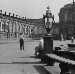 Dresden-Altstadt. Ein Mann fotografiert seine auf einer Bank im Zwingerhof sitzende Partnerin