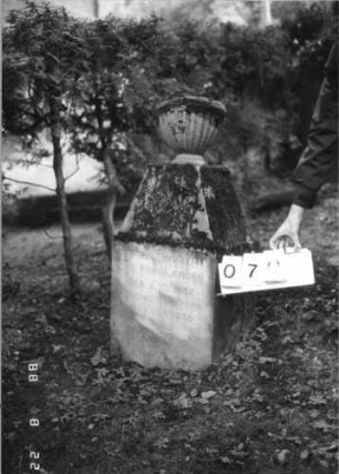 Grabstein 70 (Index: 100080197) Material: Kalk- / Kunststein? Zustand: gut, Schrift grau ausgemalt Maße HxBxT: 115x54x37 cm Beschreibung: Stele, abgeflachter Giebel mit Urnenaufsatz Symbolik: Urnenaufsatz: Grabstein 70