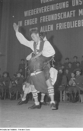 Zwei tanzende Männer in Tracht bei einer Veranstaltung zum Gedenken an die Völkerschlacht, im Hintergrund ein Orchester