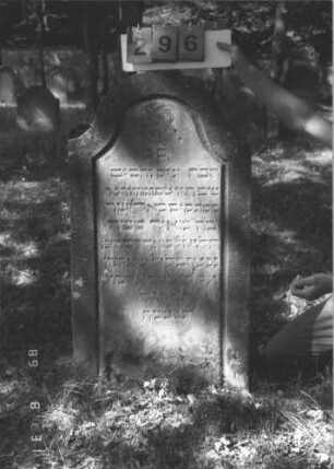 Grabstein 296 (Index: 99609933) Material: Sandstein Zustand: verwittert Maße HxBxT: 111x52x10 cm Beschreibung: Stele, Konvexbogenabschluß, Schriftfeld eingetieft Symbolik: Levitenkanne Besonderheit: Kindergrab: Grabstein 296