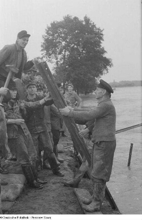 Männer bei Schutzvorkehrungen (Stabilisieren eines Dammes)