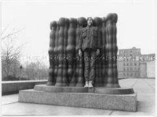 Jugendlicher posiert vor einer Skulptur (Altersgruppe 18-21)