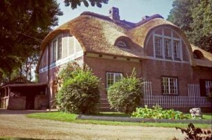 Trittauer Straße 45: Villa mit Reetdach: links Giebelseite mit Segmentgiebel, Fachwerk, Gartentür, Anbau für Brennholz: rückwärtige Traufseite, Mittelrisalit mit Segmentgiebel