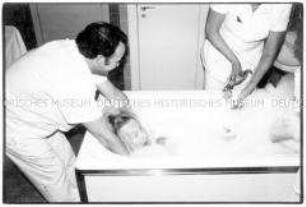 Pfleger waschen eine alte Frau in der Badewanne (Altersgruppe 18-21)