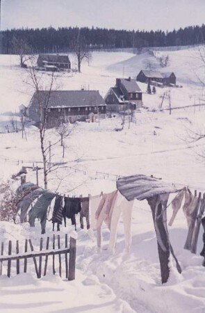 Erzgebirge. Verschneite Dorflandschaft, Kleidungsstücke auf einer Wäscheleine