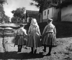 Reisefotos. Csömör. Drei Mädchen in Trachten auf der Dorfstraße