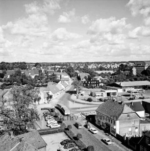 Vogelperspektive: von Silo der Weizenmühle ("Gloria-Mühle") der Johannes Ströh Mühlenwerke am Pferdemarkt: Blick nach Nordosten: vorne Straße Pferdemarkt mit Kopfsteinpflaster, Pkws, Lkw, Gaststätte "Stadt Kiel", Baulücke, Parkplatz, Hecken, Bäumchen mit Kugelschnitt, alter Baum: Mitte Kreuzung, links Pferdemarkt, nach rechts quer Berliner Ring, nach hinten Segeberger Straße mit Kopfsteinpflaster: Mitte rechts Shell-Tankstelle, rechts daneben Mercedes-Autowerkstatt, parkende Autos: hinten rechts St.-Josef-Stift [angeschnitten]