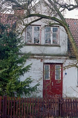Damm 5: traufständiges Wohnhaus: Straßenfront, Teilansicht: Eingangstür, Hausnummer, Zwerchhaus mit Sprossenfenstern: vorne Lattenzaun
