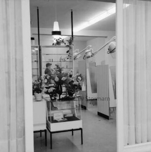 Salon Ute: Hamburger Straße: Friseursalon: Inhaberin Ute Subjetzki: Eröffnung: Innenaufnahme, Blick durch Fenster: Verkaufstheke, darauf Blumen: hinten Frau: hinten rechts Kabinen mit Trockenhauben