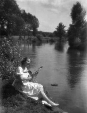 Junges Mädchen, am Ufer der Pegnitz sitzend und zur Gitarre singend