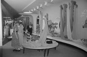 Drei Frauen begutachten eine auf der Leipziger Herbstmesse 1955 ausgestellte Stoffbahn